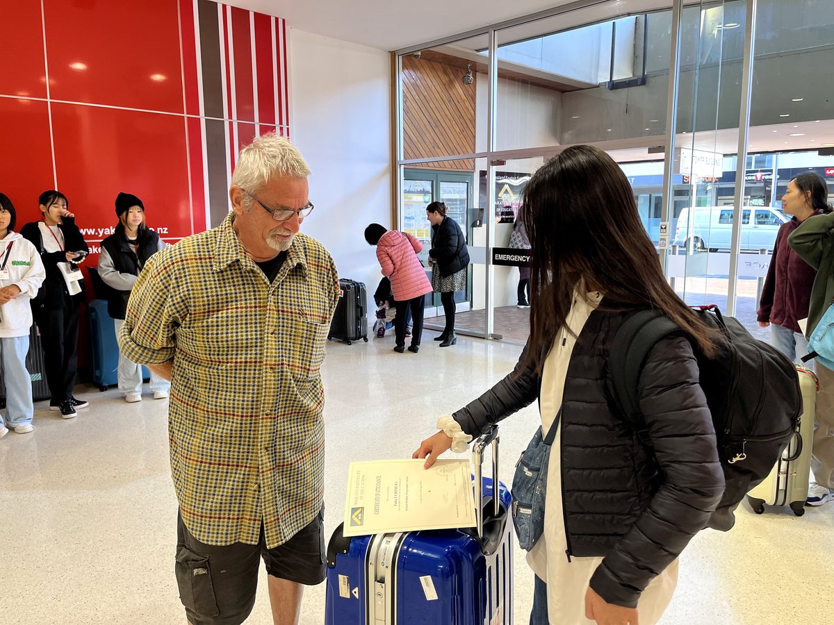 An international student showing her Waikato Institute of Education Certificate of Attendance to an older...