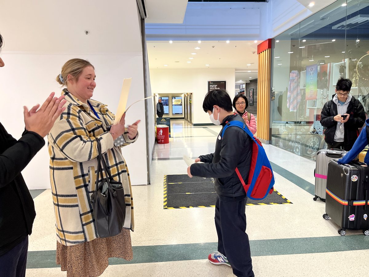 A warm moment showing a WIE staff member giving a document to a young international student in an indoor...