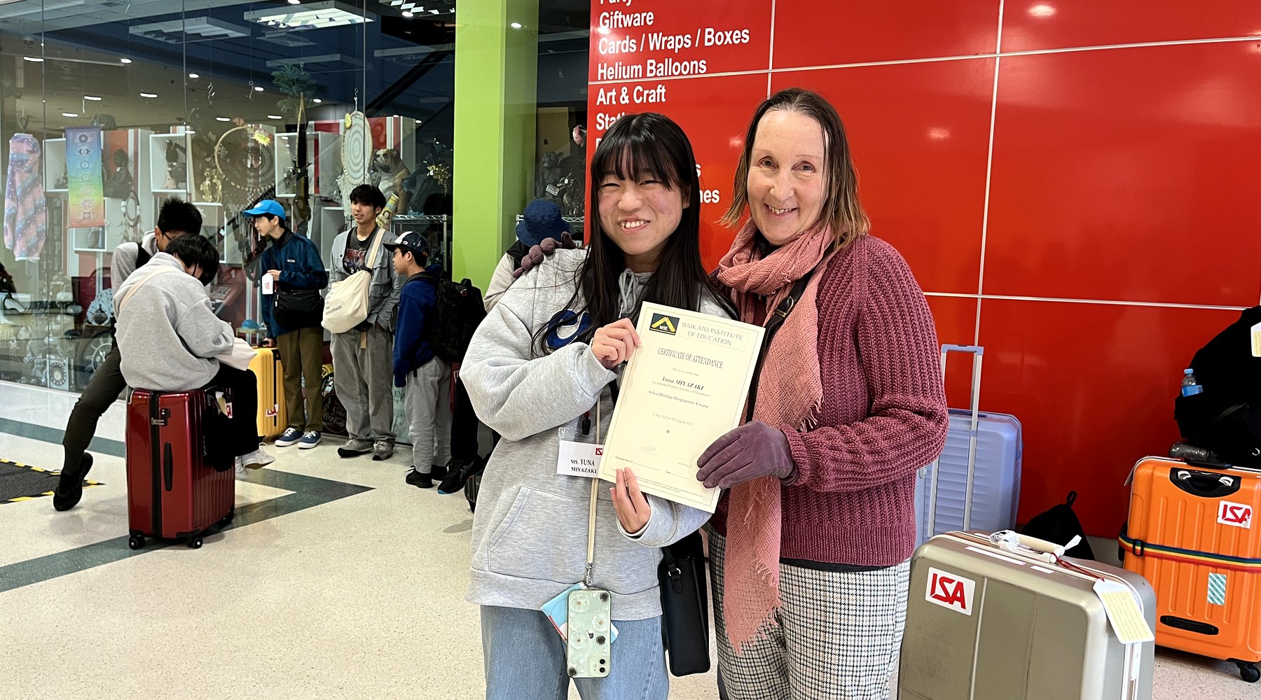 WIE student holding a completion certificate with support beside her